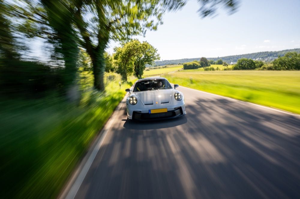 Voiture de sport grise en roulage sur une route de campagne, filé