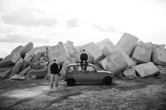 Noir et blanc : la voiture au milieu des blocs de béton, un équipier assis sur le toit